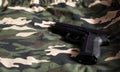 Black handgun on camouflage army green fabric