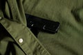 Black handgun, pistol hidden under vintage olive green military uniform