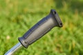 black handle of a garden tool on a grass background,close-up of a rubber black handle on a brushcutter Royalty Free Stock Photo