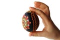 Black handmade easter egg richly decorated with traditional flower ornaments, held in hand of little child, white background