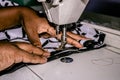 Black hands of a fashion designer sewing clothes on a sewing machine in a tailoring workshop