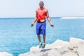 Black handsome man jumping rope with sea view in background - Male runner doing exercise and preparing for morning workout outdoor