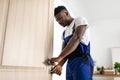 Black Handyman Wearing Coverall Uniform Fixing Door Installing Lock Indoors Royalty Free Stock Photo