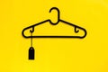 A black hanger with blank black price tag on yellow background