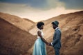 Newlyweds stand and hold hands in canyon against beautiful landscape.