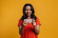 Black happy woman smiling while playing online game on cellphone Royalty Free Stock Photo