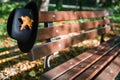 Black hat with yellow maple leaf on bench in autumn park Royalty Free Stock Photo