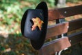 Black hat with yellow maple leaf on bench in autumn park Royalty Free Stock Photo