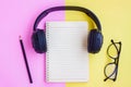 Black Headphone ,Eyeglasses,Notebook and Black pencil on pink and yellow background Royalty Free Stock Photo