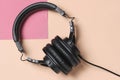 Black headphones beige pink background.