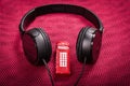 Black headphones on a knitted fabric with a red telephone booth toy in the middle Royalty Free Stock Photo