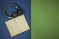 Black headphones with old open book with blank pages is lying on green and blue background. Copy space. Top view. Audio book Royalty Free Stock Photo