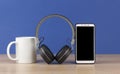 Black headphones and smart phone with stack books on wooden table againts blue wall Royalty Free Stock Photo