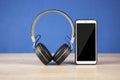 Black headphones and smart phone with stack books on wooden table againts blue wall Royalty Free Stock Photo