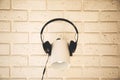 Black headphones are worn on a white lamp against the background of a white brick wall Royalty Free Stock Photo