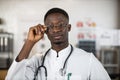 Black health care worker adjusting his eyglasses at cabinet Royalty Free Stock Photo