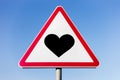 Black heart on road sign, on the background of blue sky. Royalty Free Stock Photo