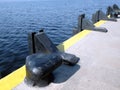 Black heavy bollards on empty pier edge on seaside diagonal view