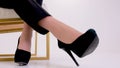 Black high-heeled platform shoes close-up female legs rearrange from one foot to the foot black short pants golden legs
