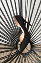 Black high-heeled shoes elegant leather women`s shoes on the rattan chair, geometry, light glossy heel shoes.