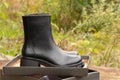 black high women's boots with thick soles lie in a box on an old board on the street, women's winter shoes Royalty Free Stock Photo