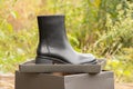 black high women's boots with thick soles lie in a box on an old board on the street, women's winter shoes Royalty Free Stock Photo
