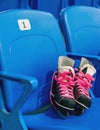 Black hockey skates with ping bootlaces on the chair on the empty stadium Royalty Free Stock Photo