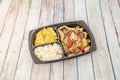 Black home delivery tray with mixed chicken and beef fajitas with corn nachos and white rice on wooden background Royalty Free Stock Photo