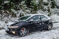 Black Honda Civic Car with Snow Chains on Front Wheels During Heavy Snowfall on Winter Season