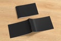 Black horizontal brochure or booklet cover mock up on wooden background. Closed one brochure and upside down other. Royalty Free Stock Photo