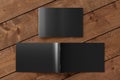 Black horizontal brochure or booklet cover mock up on wooden background. Closed one brochure and upside down other. Clipping path Royalty Free Stock Photo