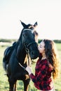 Black horse kissed by a young woman.