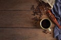 Black hot fresh coffee in brown ceramic cup with coffee beans roasted in burlap sack bag on wooden table background. Royalty Free Stock Photo