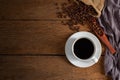 Black hot fresh coffee in a white ceramic cup with coffee beans roasted in burlap sack bag on wooden table background. Royalty Free Stock Photo