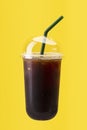 Black ice coffee in plastic cup isolated on yellow background Royalty Free Stock Photo