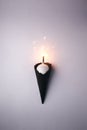 Black Ice Cream Cone with white ball and burning sparcler candle on white background, monochrome party minimal closeup.