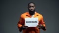 Black imprisoned male holding freedom sign in cell, asking for help human rights