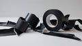 Black insulating tape roll and some torn pieces lying on white table
