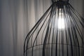 Black interior design fancy lamp with shining light bulb and white curtains in the background Royalty Free Stock Photo