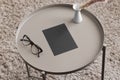 Black invitation card mockup with a candle and a glasses on the beige table. 5x7 ratio, similar to A6, A5