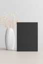 Black invitation card mockup with a gypsophila on a beige table. 5x7 ratio, similar to A6, A5