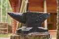 Black iron anvil on a stump in an old wooden forest village. Royalty Free Stock Photo