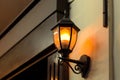 Black iron lantern in retro style illuminates wall. Royalty Free Stock Photo