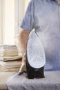 The black iron stands on the foot on the ironing board. Steam escapes from the silver part. A man ironing clothes. In the backgrou Royalty Free Stock Photo