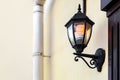 Black iron wall lantern in retro style with glass shade and electric light bulb. Royalty Free Stock Photo