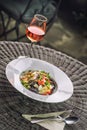 Black italian pasta with tomato sauce and parmesan, served on white plate with glass of wine, product photography for restaurant