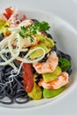 Black Italian seafood pasta with shrimps, cherry tomatoes and greens. Pasta with cuttlefish ink, cooked sea food macaroni Royalty Free Stock Photo