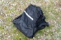 Black jacket with reflective strip crumpled on gravel and grass surface Royalty Free Stock Photo