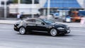 Black Jaguar XJ X351 car moving fast on the street, front side view