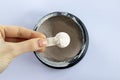 Black jar with electrolytes in measuring spoon in woman& x27;s hand on white background, top view